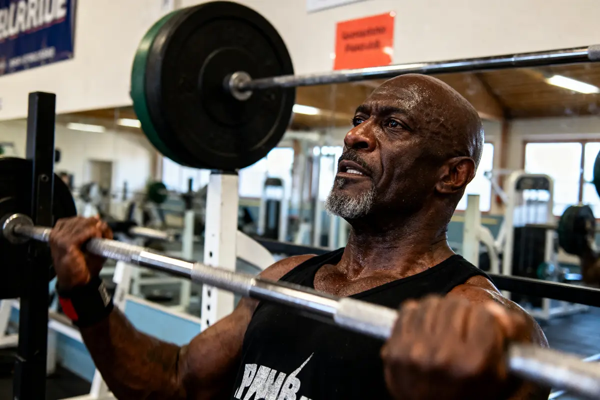 Homme musclé, levant des poids en salle de sport, concentré pendant l'entraînement, haltérophilie intense.